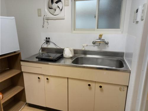 a kitchen with a sink and a microwave at アサカヤマ　ゲストハウス in Sakai