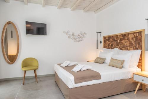 a bedroom with a large bed and a yellow chair at Lithos Luxury Suites in Tinos Town