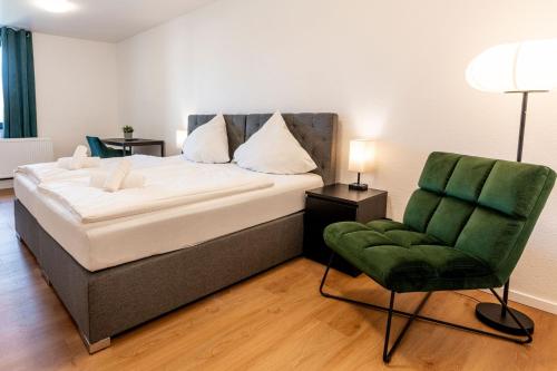 a bedroom with a bed and a green chair at Dream Factory by Hotel Bergheim in Bergheim