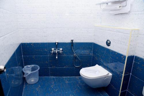 La salle de bains est pourvue de carrelage bleu, d'une douche et de toilettes. dans l'établissement Sri Vishnu Residency, à Sriperumbudur