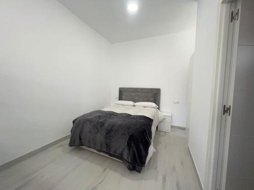 Dormitorio blanco con cama con manta negra en Estudio Playa la Misericordia, en Málaga