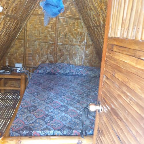 Habitación pequeña con cama en una cabaña de paja en Era's Garden Homestay en Catmon