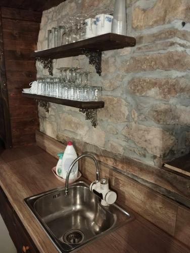 a kitchen with a sink and a stone wall at Расимова къща in Bozhentsi