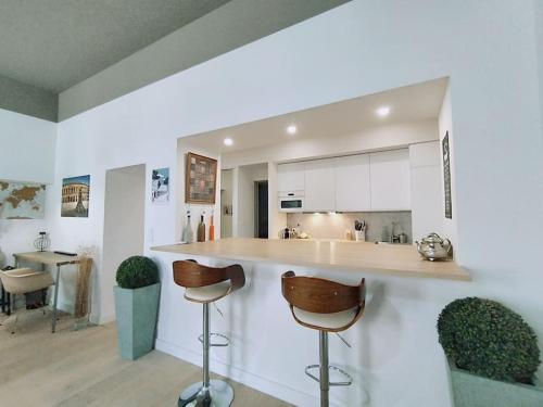 une cuisine avec un comptoir et deux tabourets de bar dans l'établissement Le Flavio à 2 pas des Arenes, à Nîmes