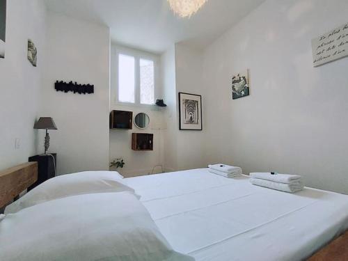 - une chambre blanche avec 2 lits blancs et une fenêtre dans l'établissement Le Flavio à 2 pas des Arenes, à Nîmes