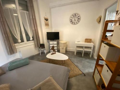a living room with a couch and a clock on the wall at Studio cosy proche centre (CDG) in Charleville-Mézières