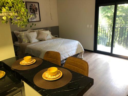 a bedroom with a bed and two tables and chairs at La Floresta Suites in Campos do Jordão