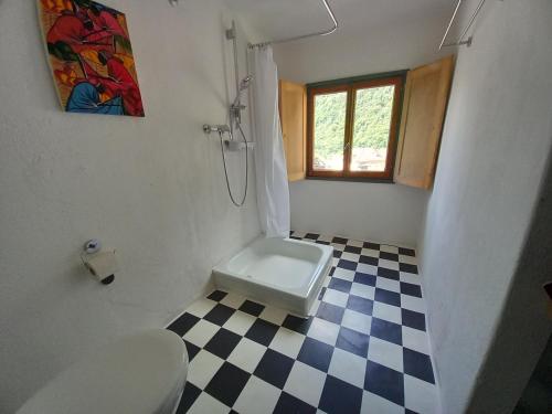 a bathroom with a toilet and a checkered floor at Room in Apartment - Casa Coerente Cavergno Room no 4 in Cevio