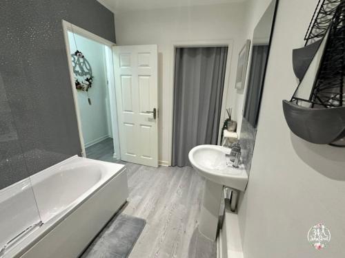 uma casa de banho com uma banheira branca e um lavatório. em COASTAL RETREAT Town Centre Entire Property, Very Close to Sea & Restaurants, 2 King Size Beds em Porthcawl