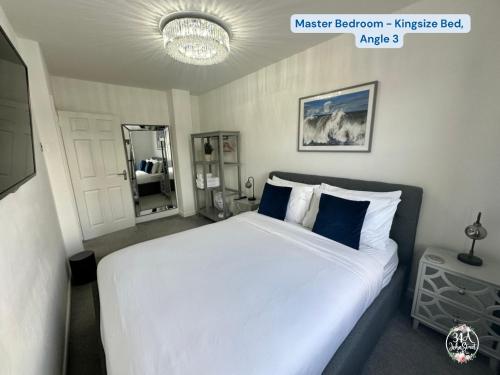 a bedroom with a large white bed with blue pillows at COASTAL RETREAT Town Centre Entire Property, Very Close to Sea & Restaurants, 2 King Size Beds in Porthcawl