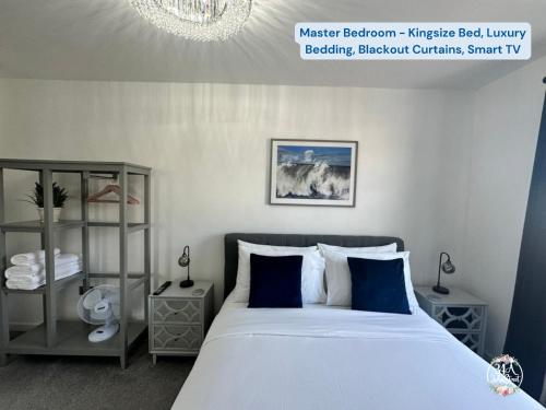 a bedroom with a large white bed with blue pillows at COASTAL RETREAT Town Centre Entire Property, Very Close to Sea & Restaurants, 2 King Size Beds in Porthcawl