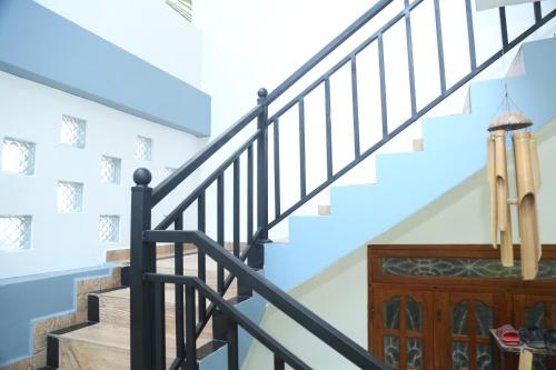 a staircase in a home with a black hand railing at Rose Fort Homestay in Jaffna