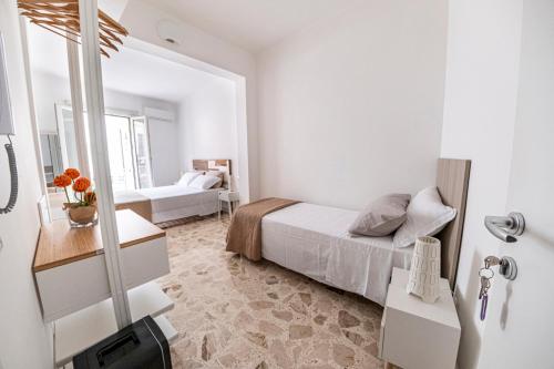 a white bedroom with a bed and a mirror at B&B - Le Tre Comari in Ragusa
