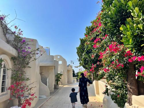 a woman and a child walking down a street with flowers at Yuki Suite Kourijima in Nakijin