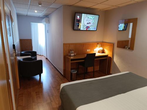 a room with a bed and a desk and a television at Mendez Nuñez Alicante in Alicante
