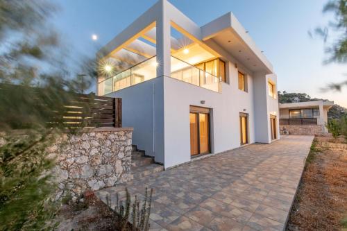 Cette grande maison blanche est dotée d'un mur en pierre. dans l'établissement Villa Cleopatra Private Heated Pool, Tennis & Football, à Koskinou