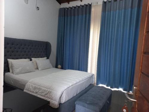 een slaapkamer met een bed en een raam met blauwe gordijnen bij Gampaha Heritage in Gampaha