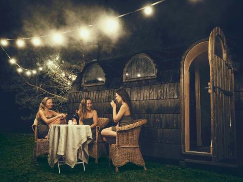 tres mujeres sentadas en una mesa frente a una casa en Bodensee Apartments, Sauna, Lake Walks, Free Parking, Self Checkin, Nature Reserve, Restaurants Nearby, en Gaißau