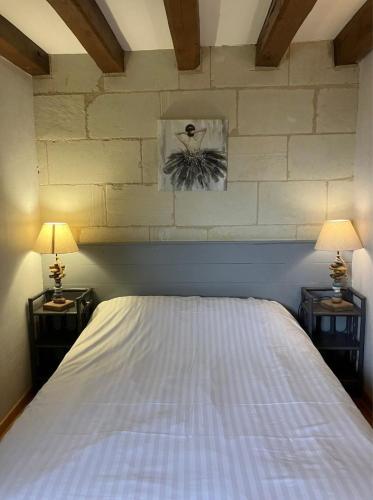 a bedroom with a bed with two nightstands and two lamps at La Bonne Note in Chinon