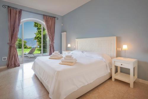 een slaapkamer met een wit bed en een groot raam bij Villa Ilaria with private pool and lake view in Torri del Benaco