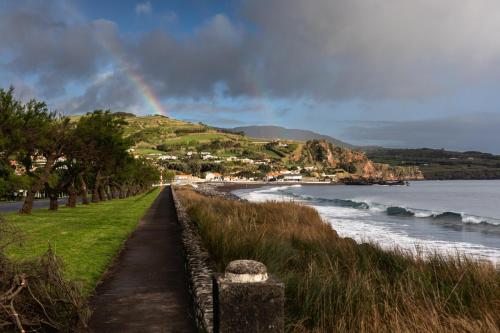 a rainbow over a beach with a path next to the water at Casinha da Praia - Beachside Retreat Almoxarife in Praia do Almoxarife