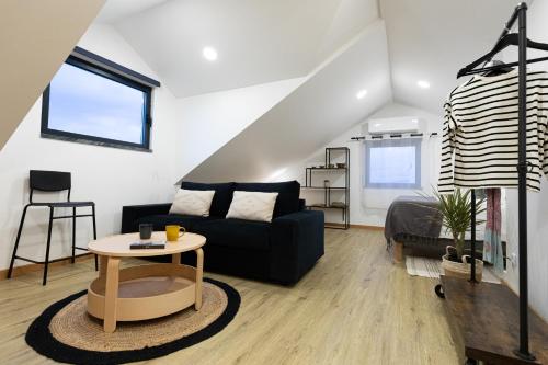 a living room with a black couch and a table at Casinha da Praia - Beachside Retreat Almoxarife in Praia do Almoxarife