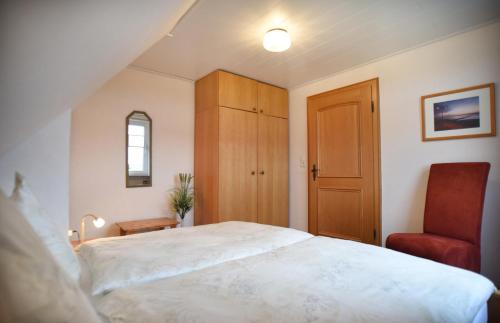 ein Schlafzimmer mit einem großen weißen Bett und einem Stuhl in der Unterkunft Dünenstübchen Baltrum in Baltrum