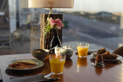 Hotel Noordzee في كاتفايك: طاولة مع أطباق من الطعام وكأسين من عصير البرتقال