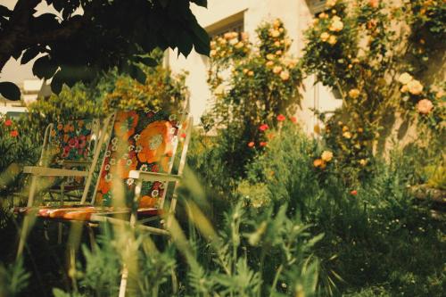 a chair sitting in a garden with flowers at Chez Ric et Fer in Coucy-le-Château-Auffrique