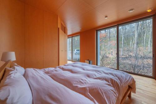 a bedroom with a large bed and a large window at NASU PRIVATE FOREST: 広大な森の中のモダンハウス in Shiozawa
