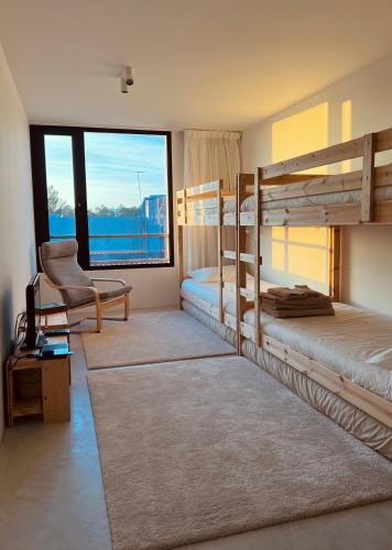 a bedroom with two bunk beds and a chair at Square House . Comporta, Portugal in Comporta