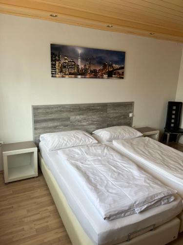 ein Schlafzimmer mit einem weißen Bett mit einem Bild an der Wand in der Unterkunft Pension Unterreichenbach in Schwabach