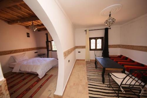 a bedroom with a bed and a table and a couch at Riad Villa Dades in Boumalne