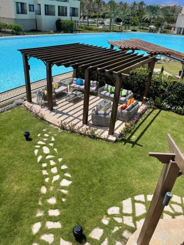 a wooden picnic table in the grass next to a pool at Marassi Blanca in El Alamein