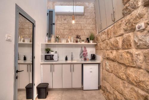 a kitchen with white cabinets and a stone wall at קשתות - מתחם אבן בצפת העתיקה - Kshatot - Stone Complex in Old Tzfat in Safed