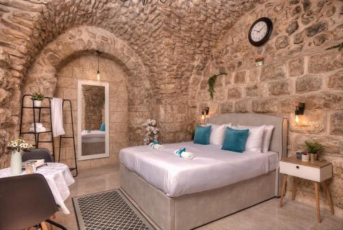 ein Schlafzimmer mit einem Bett in einer Steinmauer in der Unterkunft קשתות - מתחם אבן בצפת העתיקה - Kshatot - Stone Complex in Old Tzfat in Safed