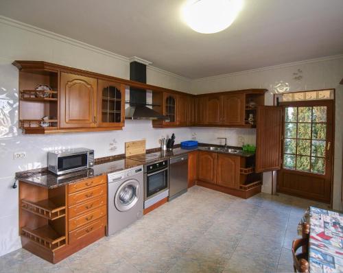 cocina con armarios de madera, lavadora y secadora en Casa los Arcos, en Trespaderne