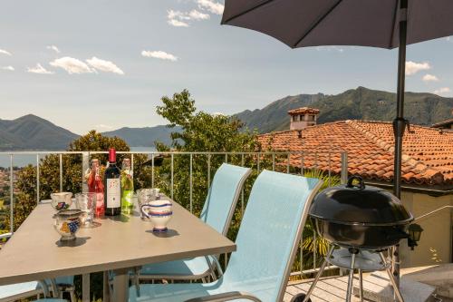 une table et des chaises avec un parasol et un grill dans l'établissement Casa Teatro Panoramico 5 Star Holiday House, à Locarno