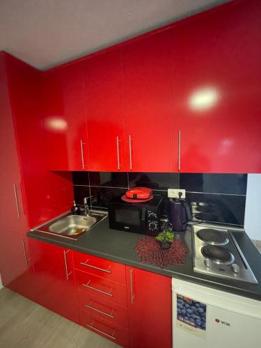 a red kitchen with a stove and a sink at SWEET apartment near Old Town in Mostar