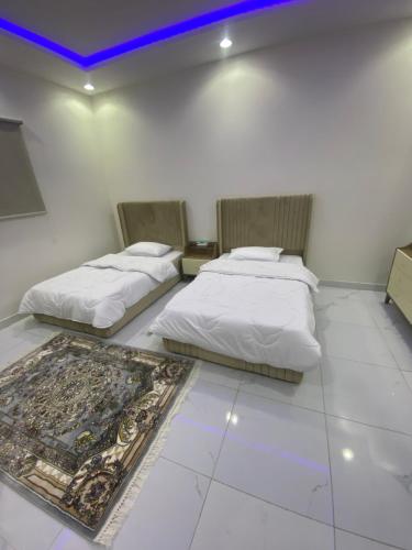 a bedroom with two beds and a rug on the floor at شقق الريان للعزاب والعوائل in Hafr Al Baten