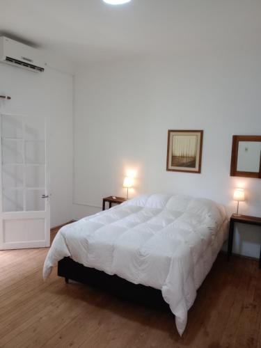 um quarto com uma grande cama branca e 2 candeeiros em Sofia em Montevidéu