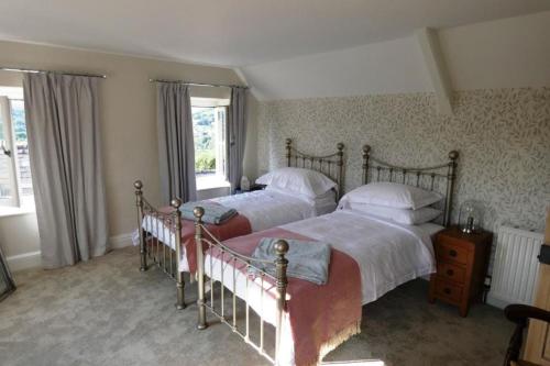 a bedroom with two beds and two windows at Cotswolds cottage near Stroud, with amazing views. in Brimscombe