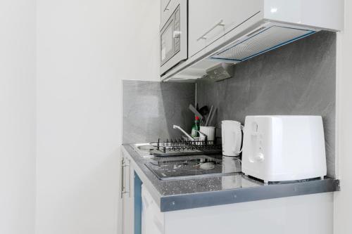 a small kitchen with a white microwave and a stove at London Central Studios in London