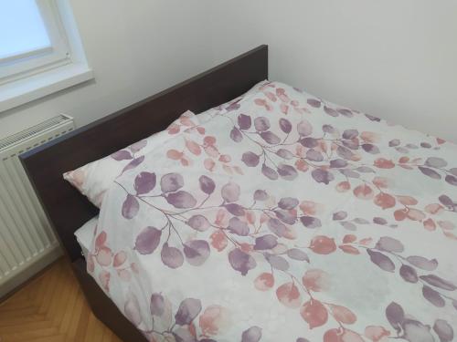 een bed met een bloemdekbed erop bij Apartman Centar 1 in Bijeljina