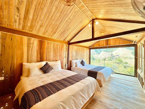 a bedroom with two beds in a wooden room at Na Thẩm Eco Hill Homestay - Trạm Tấu in Cham Ta Lao