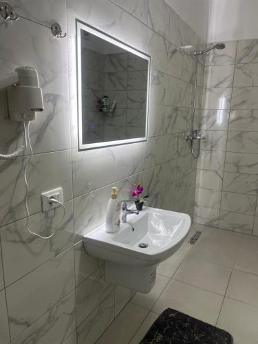 a white bathroom with a sink and a mirror at Access apartment in Tirana