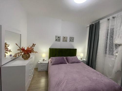 a bedroom with a purple bed and a white dresser at Access apartment in Tirana