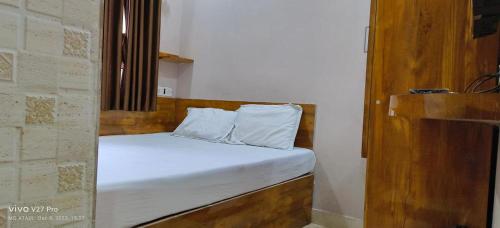 a bed with white sheets and pillows in a room at M.M.LODGE in Kolkata