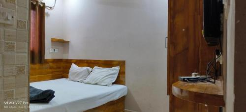 a bedroom with a bed with white sheets and pillows at M.M.LODGE in Kolkata