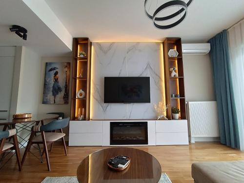 una sala de estar con TV en un centro de entretenimiento blanco en Anika Luxury apartment at Diamond center, en Skopje
